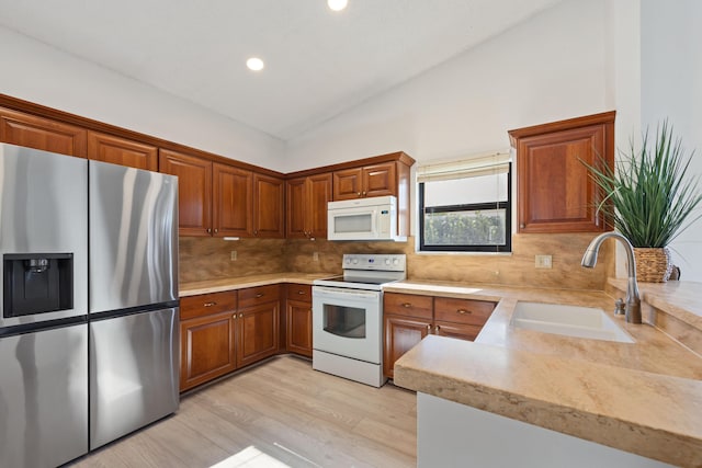 kitchen featuring lofted ceiling, backsplash, white appliances, sink, and light hardwood / wood-style flooring