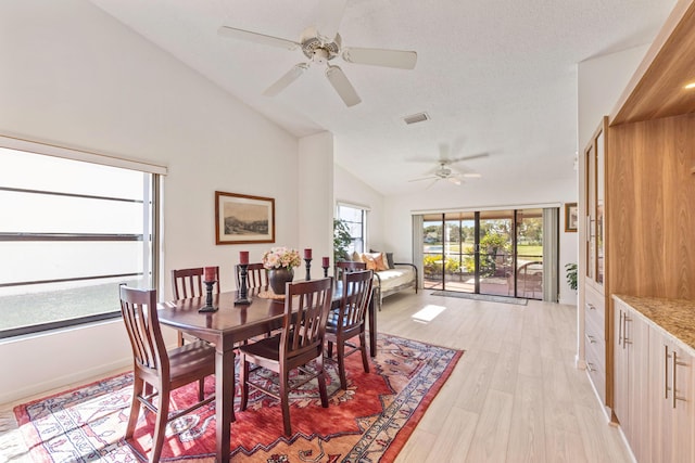 dining room featuring ceiling fan, light wood-type flooring, lofted ceiling, and a textured ceiling