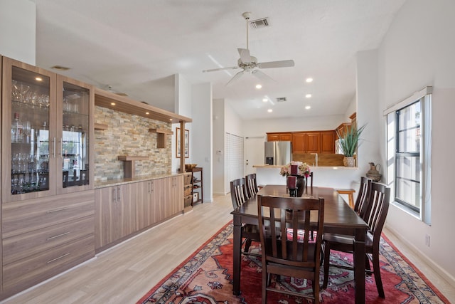 dining area featuring ceiling fan, light hardwood / wood-style floors, and vaulted ceiling