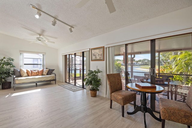 sitting room featuring ceiling fan, a water view, a textured ceiling, and light wood-type flooring