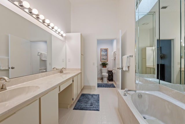 bathroom featuring tile patterned floors, tiled bath, vanity, and toilet