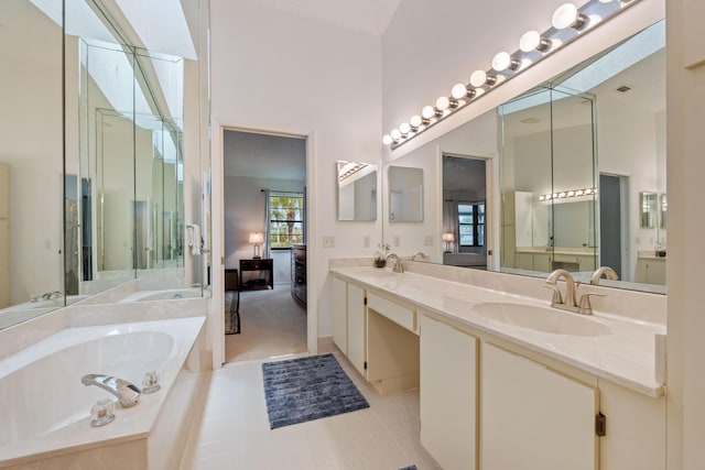 bathroom with tile patterned floors, vanity, a towering ceiling, and tiled tub