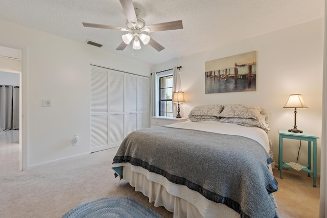 carpeted bedroom with ceiling fan, a closet, and a textured ceiling