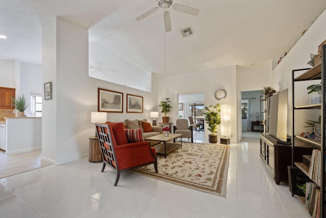 living room with ceiling fan, a textured ceiling, and a high ceiling