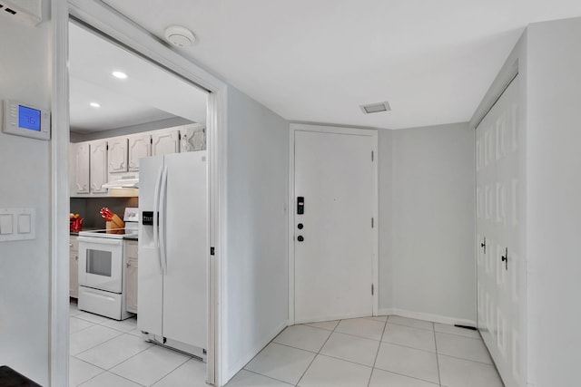 kitchen with white cabinetry, white appliances, and light tile patterned floors