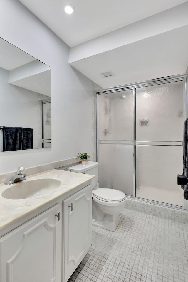 bathroom featuring tile patterned floors, vanity, a shower with shower door, and toilet