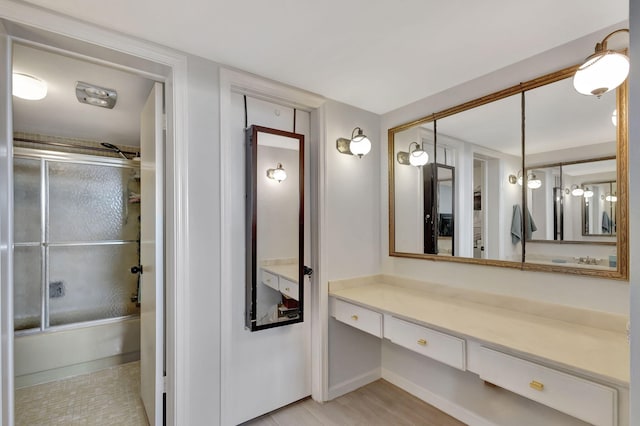 bathroom featuring hardwood / wood-style flooring, vanity, and bath / shower combo with glass door