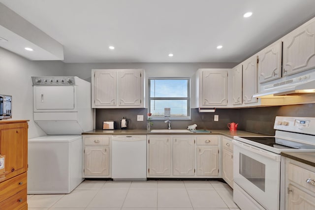 kitchen with stacked washer / dryer, light tile patterned flooring, white appliances, and sink