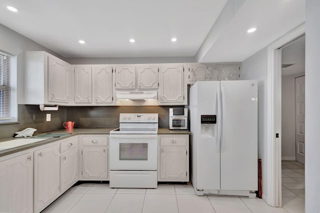 kitchen featuring white cabinets, sink, light tile patterned floors, and white appliances