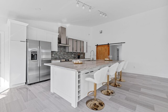 kitchen with white cabinetry, sink, a wealth of natural light, a barn door, and a kitchen island with sink