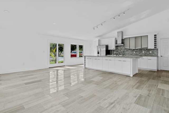 kitchen with sink, wall chimney exhaust hood, stainless steel refrigerator with ice dispenser, vaulted ceiling, and decorative backsplash