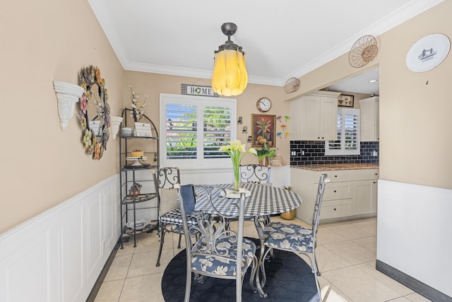 dining room featuring a wainscoted wall, ornamental molding, and a healthy amount of sunlight