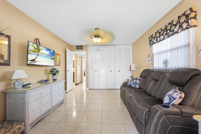 tiled living room featuring ceiling fan and a textured ceiling