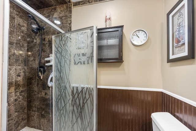 bathroom with wood walls, toilet, and tiled shower