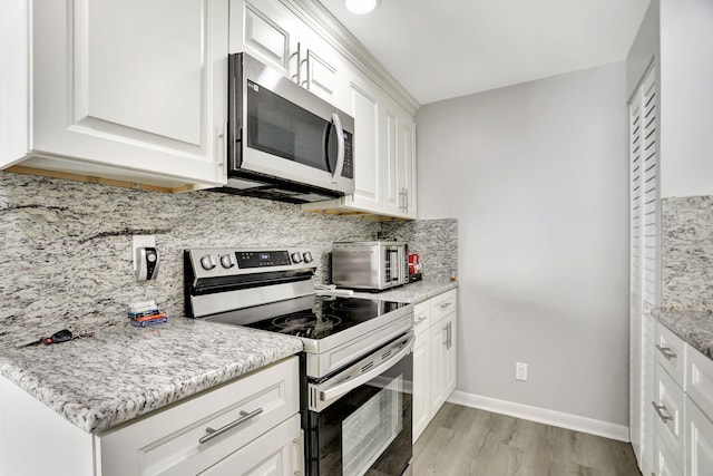 kitchen featuring stainless steel appliances, light hardwood / wood-style flooring, white cabinetry, and light stone countertops