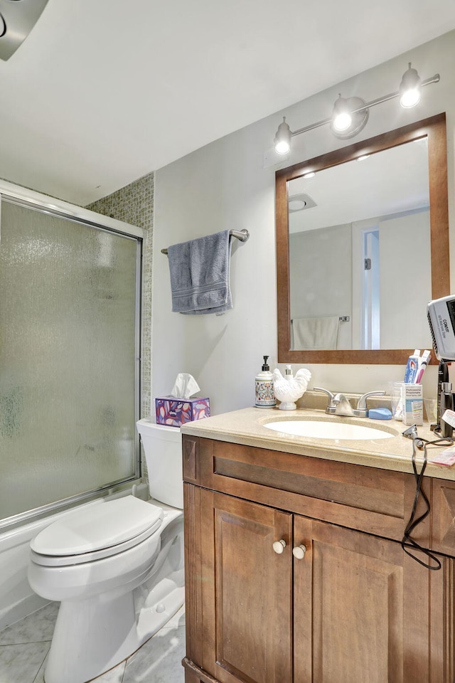 full bathroom featuring toilet, bath / shower combo with glass door, tile patterned flooring, and vanity