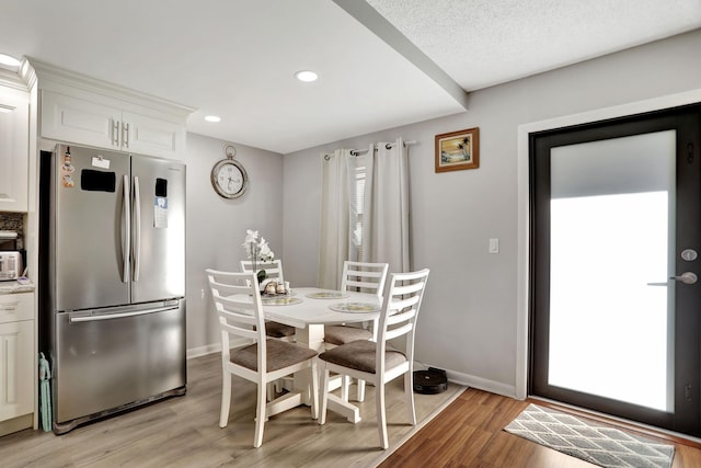 dining area with a textured ceiling and light hardwood / wood-style flooring