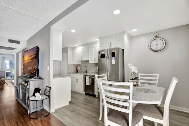 kitchen featuring appliances with stainless steel finishes, white cabinetry, decorative backsplash, sink, and dark hardwood / wood-style floors