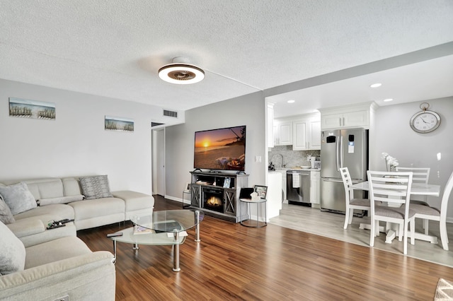 living room with wood-type flooring, sink, and a textured ceiling