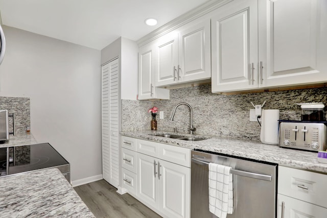 kitchen with light stone countertops, appliances with stainless steel finishes, sink, and white cabinetry