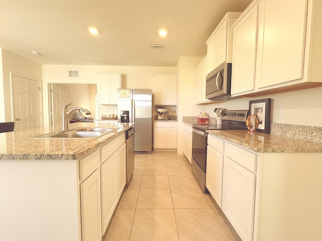 kitchen featuring sink, white cabinetry, a center island with sink, light tile patterned floors, and appliances with stainless steel finishes