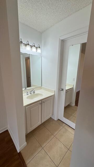 bathroom with tile patterned flooring, a textured ceiling, and vanity