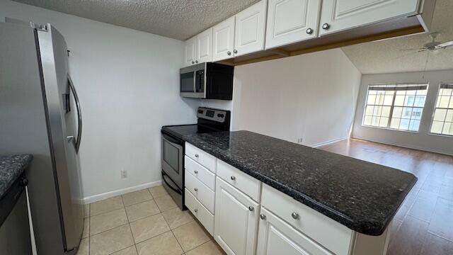 kitchen with white cabinets, kitchen peninsula, stainless steel appliances, and a textured ceiling