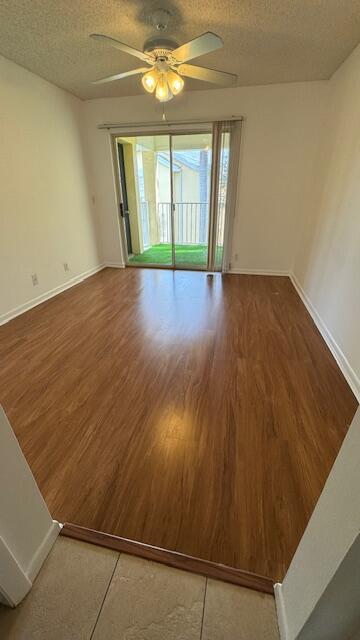 empty room with hardwood / wood-style flooring, ceiling fan, and a textured ceiling