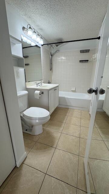 full bathroom with tile patterned floors, a textured ceiling, toilet, vanity, and tiled shower / bath