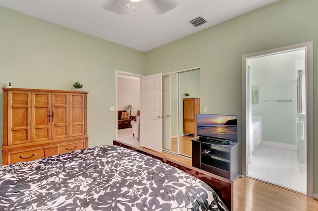 bedroom featuring ensuite bath, ceiling fan, light wood-type flooring, and a closet