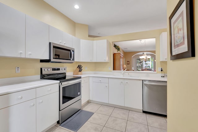 kitchen featuring light tile patterned floors, appliances with stainless steel finishes, a chandelier, white cabinets, and sink