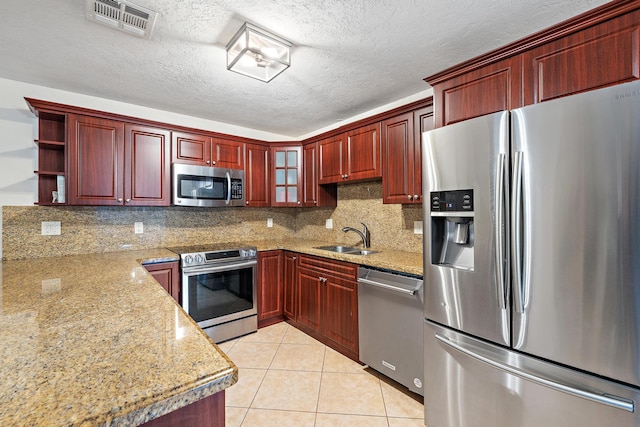 kitchen with decorative backsplash, sink, light stone countertops, and stainless steel appliances