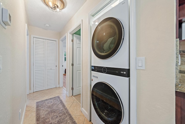 laundry room with light tile patterned floors, a textured ceiling, and stacked washer / drying machine