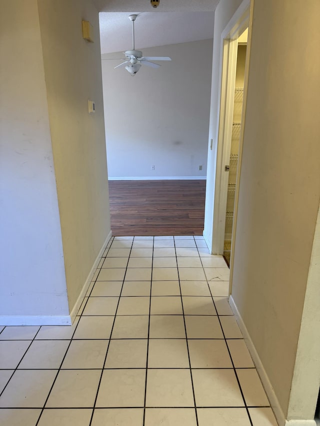 corridor featuring light tile patterned flooring and lofted ceiling