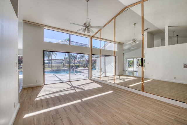 unfurnished living room featuring light hardwood / wood-style floors, high vaulted ceiling, and ceiling fan