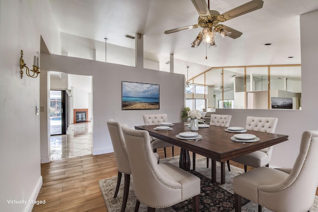 dining area featuring a high ceiling, light hardwood / wood-style flooring, a wealth of natural light, and ceiling fan