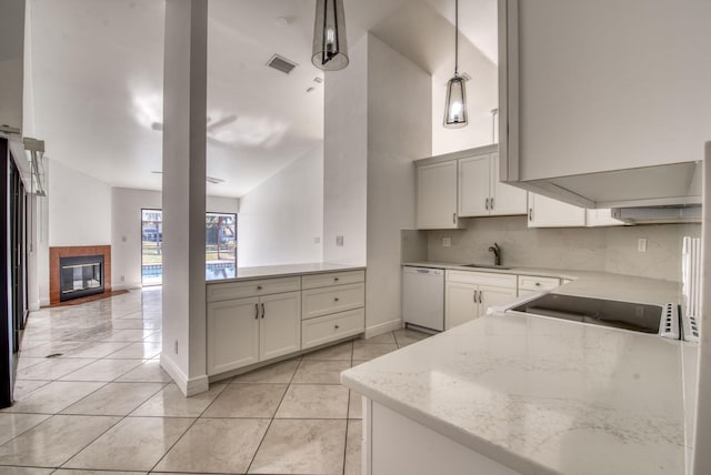 kitchen with light stone countertops, sink, a tile fireplace, decorative light fixtures, and dishwasher