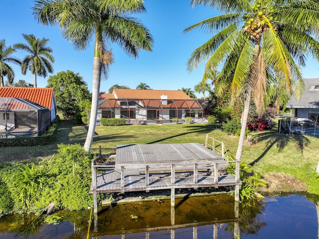 dock area with a water view, glass enclosure, and a lawn