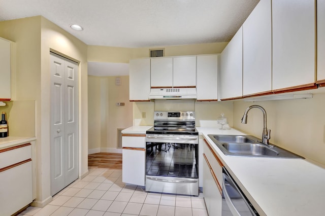 kitchen with a textured ceiling, stainless steel appliances, sink, light tile patterned floors, and white cabinetry