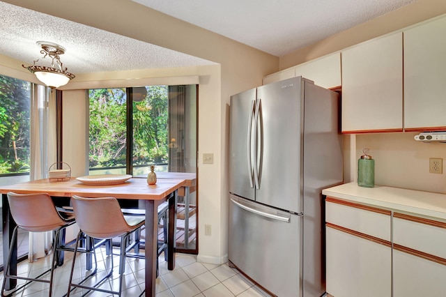 kitchen featuring white cabinets, stainless steel fridge, a textured ceiling, and plenty of natural light