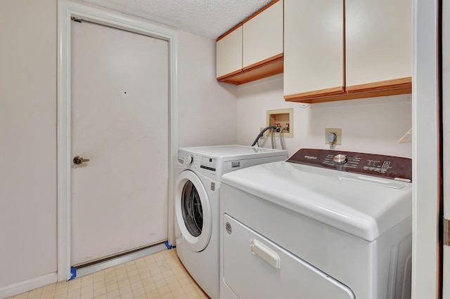 laundry room with washer and dryer, cabinets, and a textured ceiling