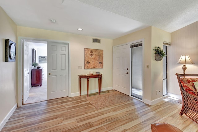 foyer entrance featuring a textured ceiling and light hardwood / wood-style flooring