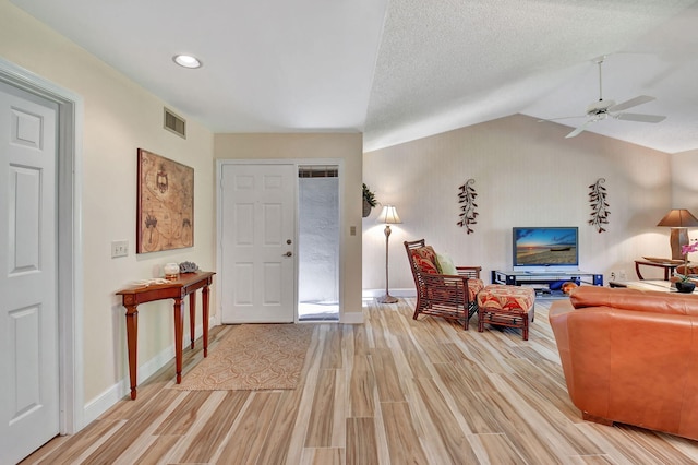 entrance foyer featuring ceiling fan, lofted ceiling, a textured ceiling, and light hardwood / wood-style flooring