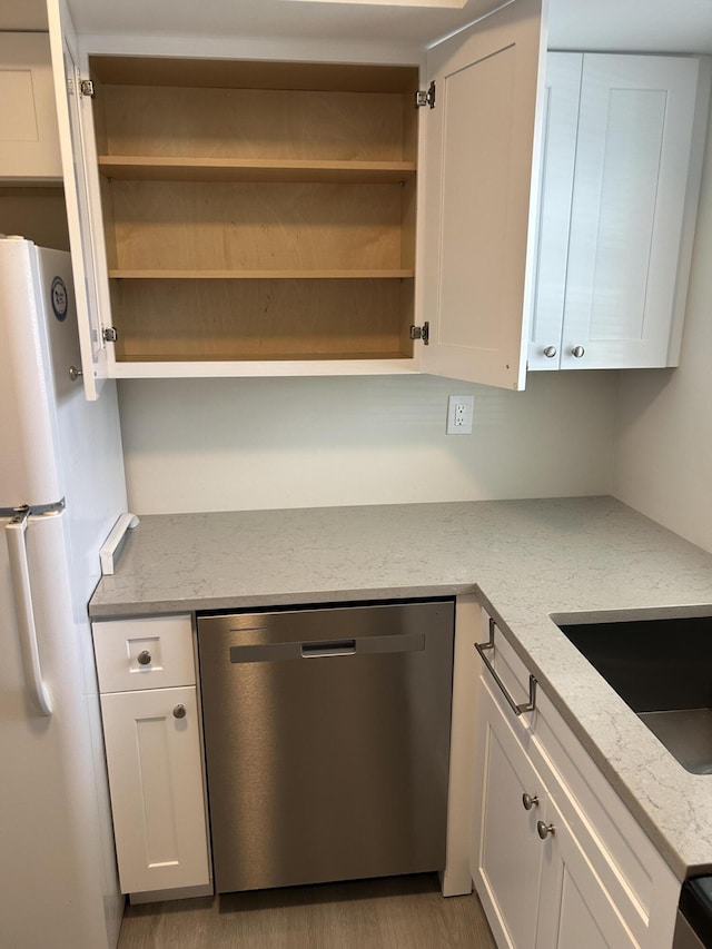 kitchen featuring white cabinets, stainless steel dishwasher, light stone countertops, light wood-type flooring, and white fridge