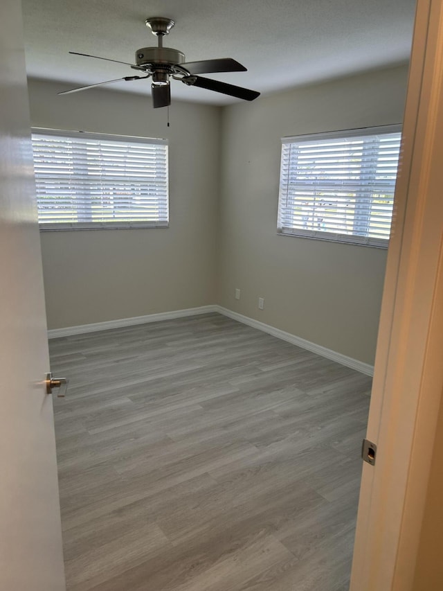 empty room with ceiling fan, a healthy amount of sunlight, and light wood-type flooring