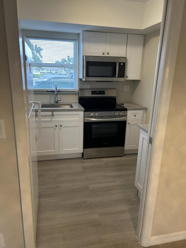 kitchen featuring white cabinets, sink, stainless steel appliances, and light hardwood / wood-style flooring