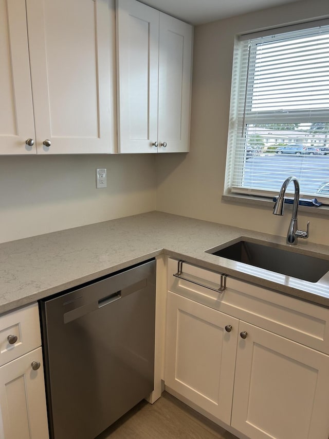 kitchen with light stone counters, dishwasher, white cabinets, and sink