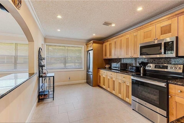 kitchen featuring stainless steel appliances, dark stone countertops, a textured ceiling, decorative backsplash, and ornamental molding