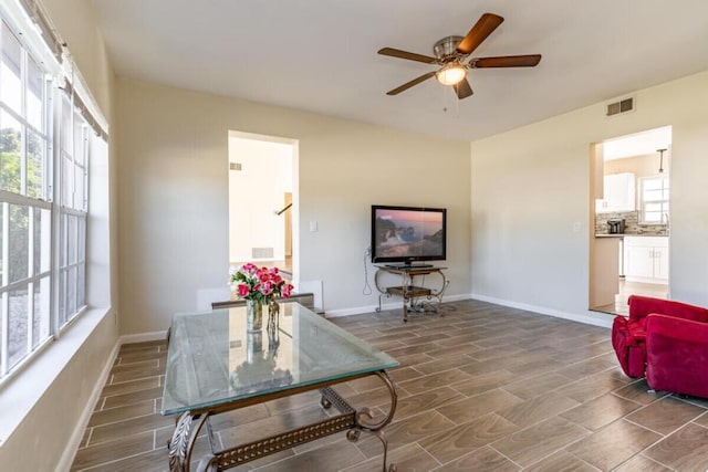 living room with a wealth of natural light, ceiling fan, and dark hardwood / wood-style floors