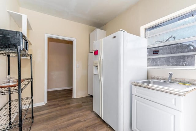 kitchen featuring white fridge with ice dispenser, white cabinets, dark wood-type flooring, and sink